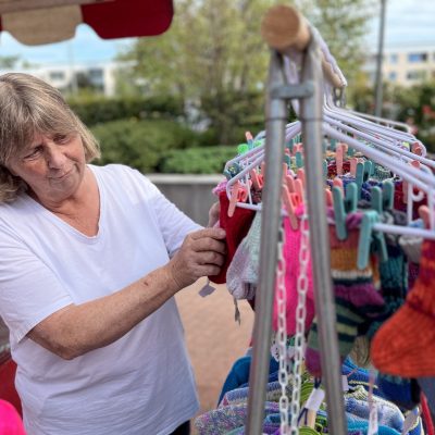 En kvinna visar stickade varor vid ett marknadsstånd